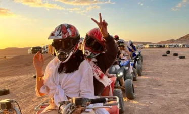 sortie-quad-groupe-agafay-marrakech.webp Alt : Groupe de touristes en quad avec casques au coucher du soleil dans le désert d'Agafay